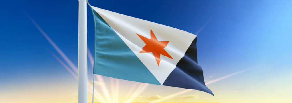 The Syracuse city flag waving on a flagpole against a blue sky at sunrise.